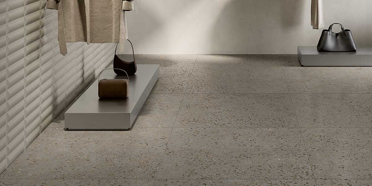 Bits Grey terrazzo-look porcelain floor tile in a contemporary retail interior with textured wall tile.